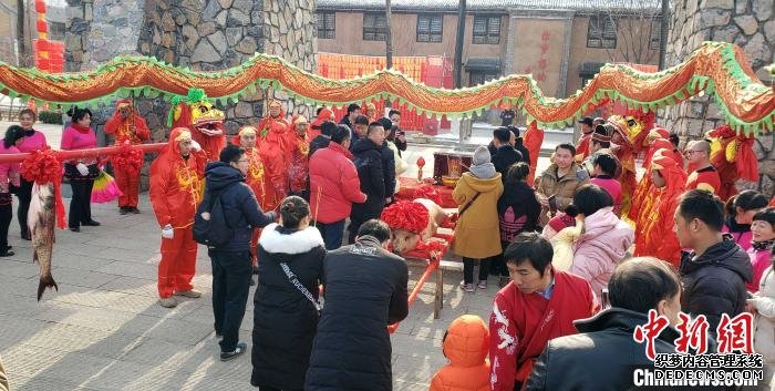民间传统祭灶神活动引游客参与。　徐巧明 摄