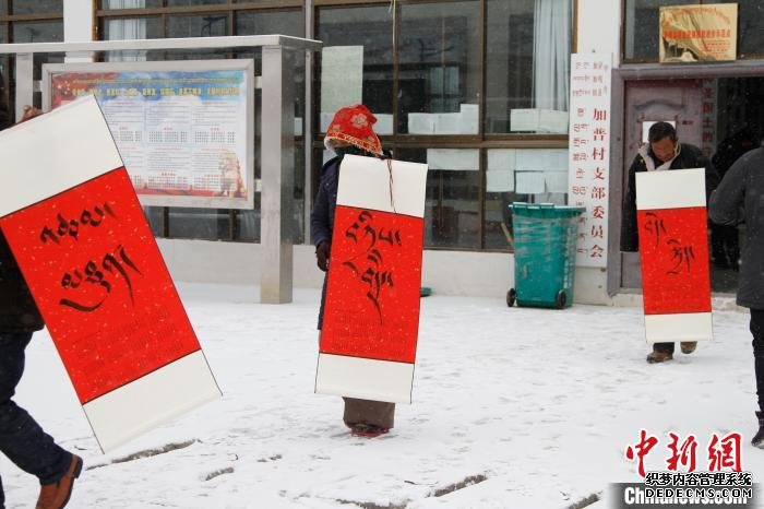 图为萨嘎县加加镇村民拿着新年书法雪中归家。　赵朗 摄